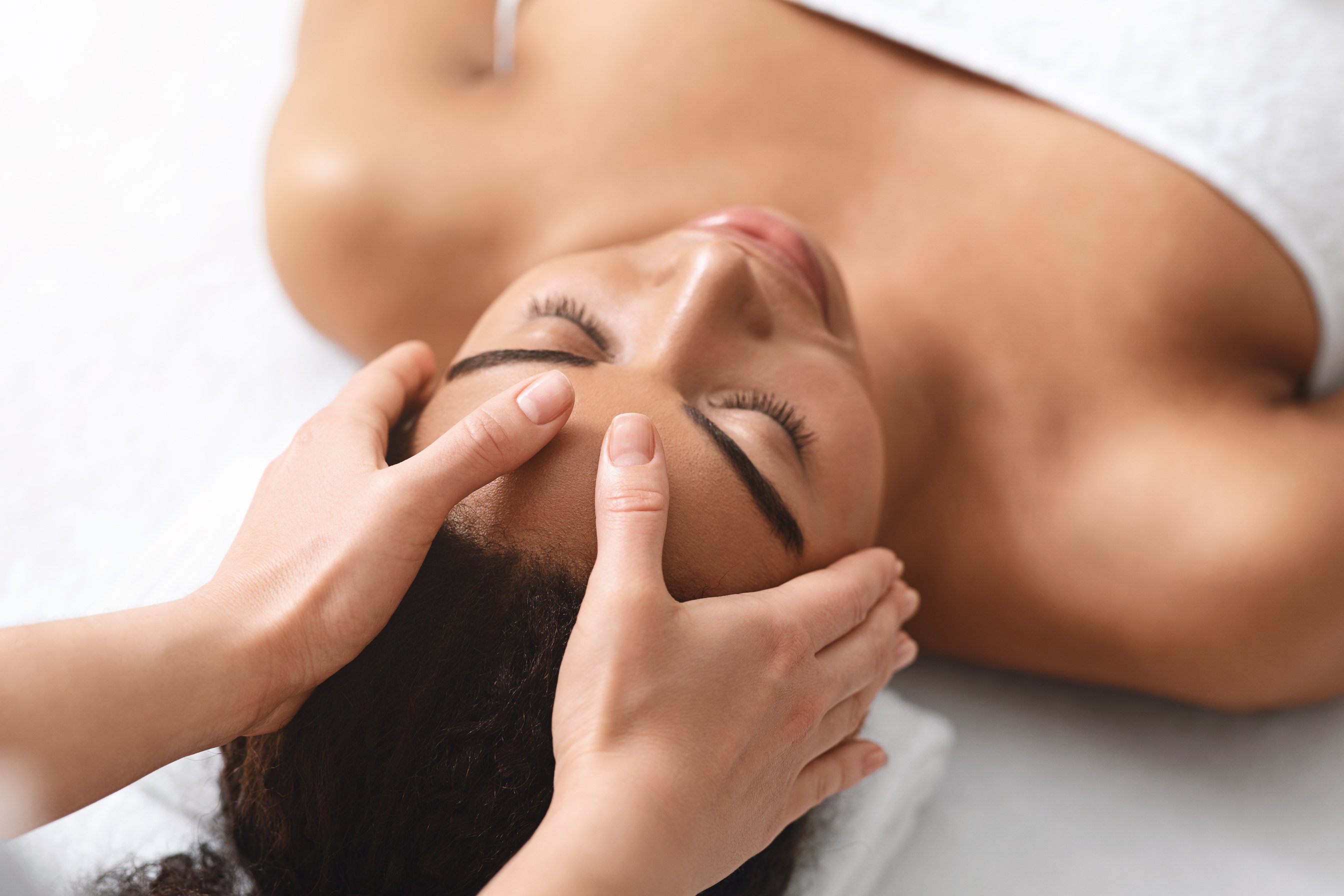 Unrecognizable therapist making acupressure head massage for young woman